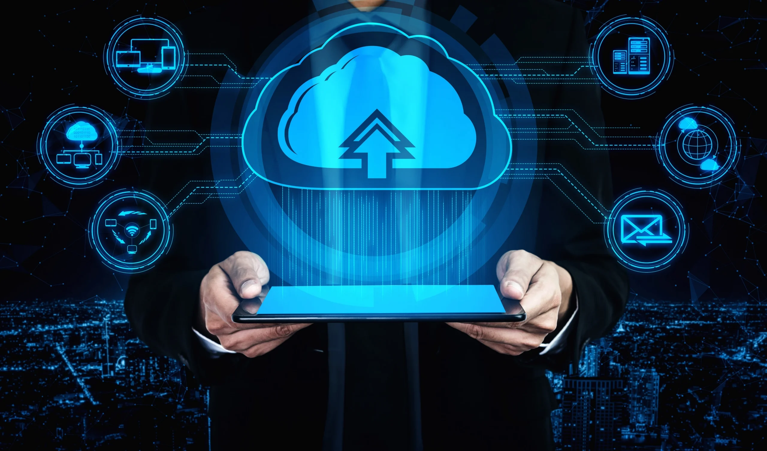 Businessman holding a tablet with a glowing blue cloud upload icon, surrounded by digital cloud computing and network technology symbols on a dark background.