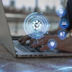 Person typing on a laptop with digital icons representing quality control, data analysis, process automation, and cybersecurity overlayed on the screen.